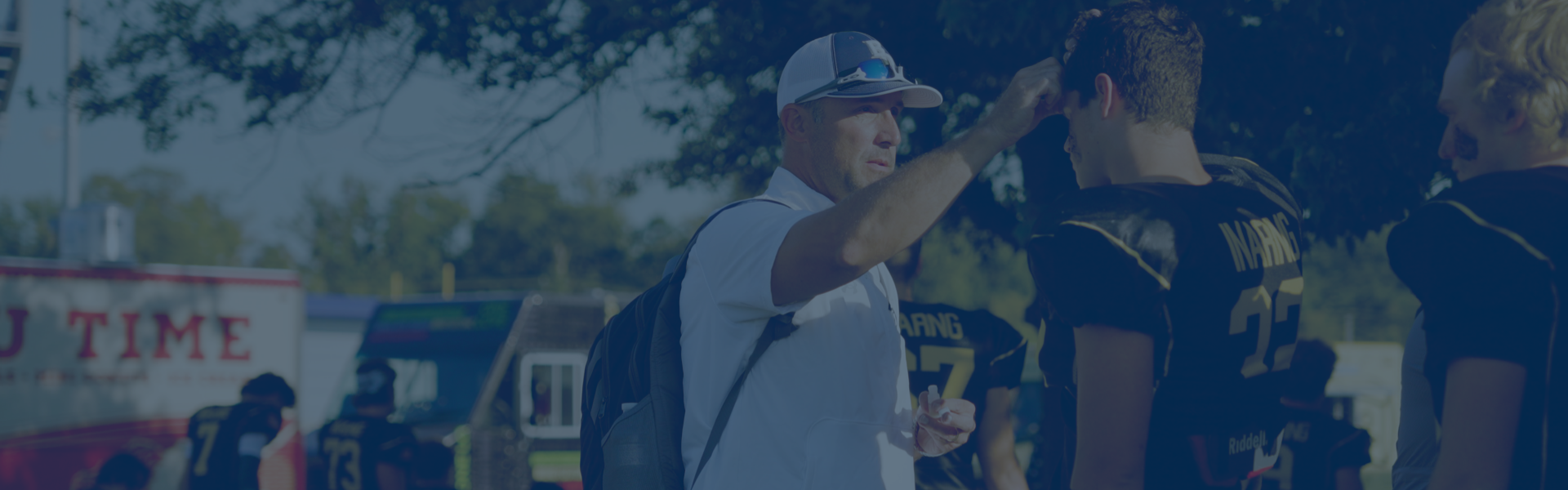 A coach is shown interacting with a football player.